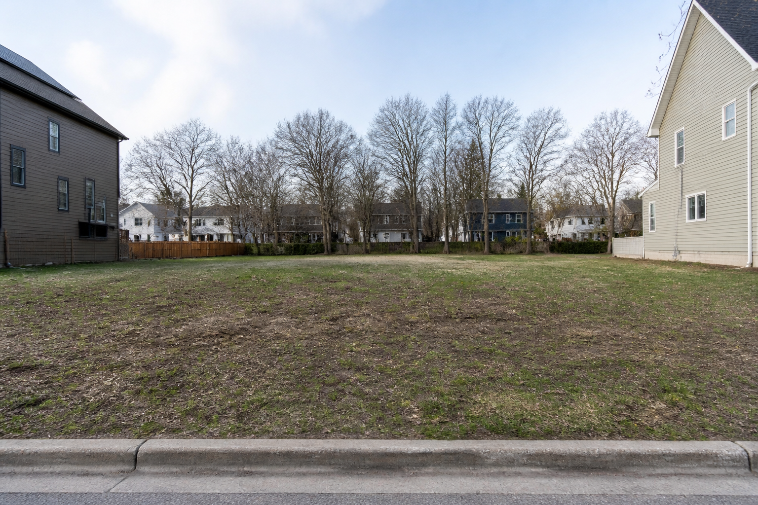 A vacant grassy city lot between neighborhood houses